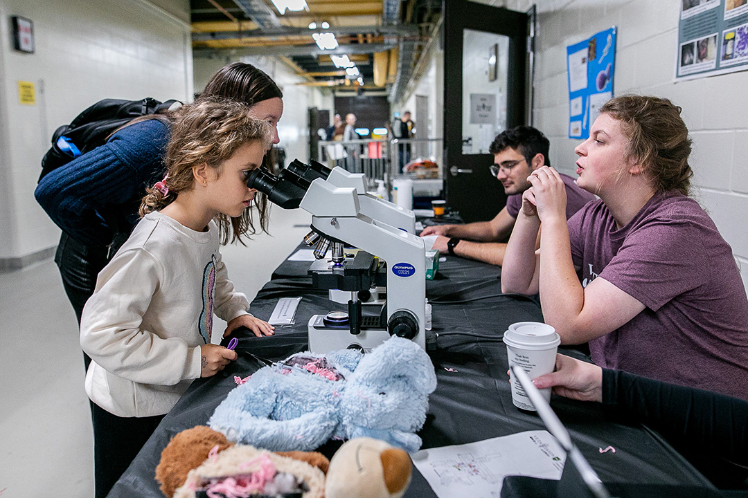 Young children peer through microscopes at a display